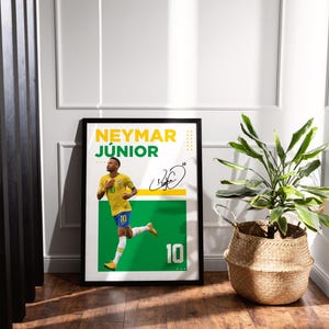 May include: Framed poster featuring Neymar J&uacute;nior in a yellow and blue soccer uniform, with the number 10. The poster has a green and white background with the player's signature and the name "NEYMAR J&Uacute;NIOR" in yellow and green.