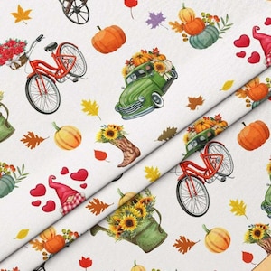Puede incluir: Una tela blanca con un patrón repetitivo de bicicletas rojas, camiones antiguos verdes, calabazas naranjas, girasoles en botas, girasoles en regaderas, gnomos rojos y corazones rojos, intercalados con varias hojas de otoño coloridas.