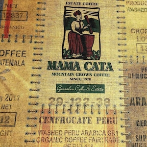 May include: A close-up of a burlap coffee sack with the text "ESTATE COFFEE" at the top. The sack features a graphic of a woman with a mortar and pestle, the words "MAMA CATA" and "MOUNTAIN GROWN COFFEE SINCE 1970".
