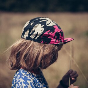 May include: A person wearing a black, pink, and white patterned cycling cap with a long, brown hairstyle.