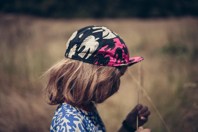 May include: A person wearing a black, pink, and white patterned cycling cap with a long, brown hairstyle.