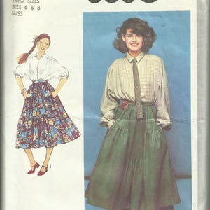 May include: A sewing pattern for a skirt and blouse. The pattern is for sizes 6 and 8. The skirt is a tiered skirt with a high waist. The blouse has a collar and long sleeves. The pattern is from Simplicity and the pattern number is 8680.