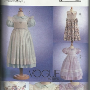 May include: A sewing pattern for a girl's dress. The pattern includes four different styles: a white dress with a blue collar and sleeves, a floral print dress, a pink and white gingham dress, and a white dress with a blue collar and sleeves. The pattern is from Vogue Patterns and is designed by Teresa Layman.