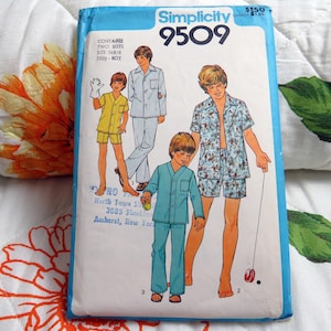 以下が含まれることがあります： Simplicity 9509の裁縫型紙封筒。半袖や長袖のトップスにショートパンツやズボンを合わせた様々なパジャマセットを着た4人の人物のイラストが描かれています。青と白のパッケージにはSimplicity 9509という文字が表示されています。
