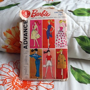 May include: A vintage Barbie Mattel teen age fashion doll pattern envelope by Advance. The paper packet features six illustrated outfits in numbered panels with red, pink, and orange backgrounds, displaying various dresses and casual clothing styles.