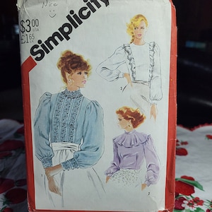 May include: Simplicity sewing pattern number 5484 for a blouse with a ruffled collar and long sleeves. The pattern includes three different views, each with a different style of collar and sleeve. The pattern is priced at $3.00 USD and £1.65 GBP.