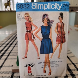 May include: Vintage Simplicity sewing pattern packet, featuring illustrations of three dresses. The packet is labeled "8832 Simplicity" and includes size and measurement details. The packet also includes the text "Jiffy" and "Mary Lester Fabrics".