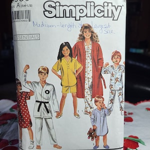 Puede incluir: Patrón de costura Simplicity Essentials con ilustraciones de ropa de dormir y batas para niños y adultos. El patrón incluye pijamas, un uniforme de karate y una bata. El paquete es blanco con texto en negro y azul.