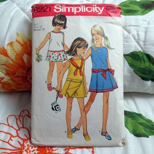 May include: A vintage Simplicity 8221 sewing pattern envelope for a girl's size 12, breast 30, featuring illustrations of three outfits: a white floral top and shorts, a yellow collared dress, and a blue dress with a red polka dot sash.