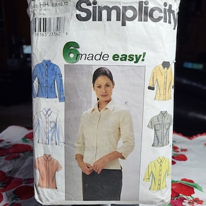 May include: A Simplicity sewing pattern packet featuring illustrations of six different shirt designs. The packet includes a photo of a woman wearing a cream-colored shirt. The text "Simplicity" and "6 made easy!" are visible.