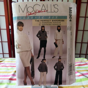 Może przedstawiać: McCall's Classic Fit wzór szycia M5964. Wzór przedstawia obrazy kostiumu ze spódnicą, żakietu ze spódnicą i spodnium. Tekst na wzorze brzmi "The Perfect Wardrobe" w języku angielskim, francuskim i hiszpańskim.