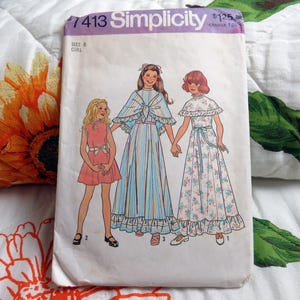 Pode incluir: Um envelope de molde de costura Simplicity 7413 para um vestido de menina tamanho 8. A frente apresenta uma ilustração de três figuras vestindo diferentes estilos de vestidos, incluindo um vestido curto, um vestido listrado com capa e um floral.