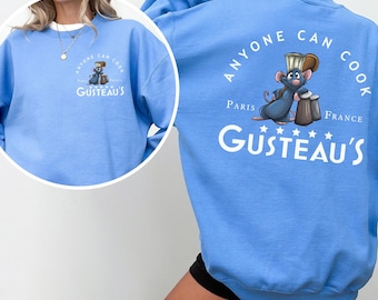 May include: Carolina blue sweatshirt featuring a cartoon rat chef with the text "Anyone Can Cook" and "Gusteau's" in white. The back of the sweatshirt has the same design with "Paris France" and stars.
