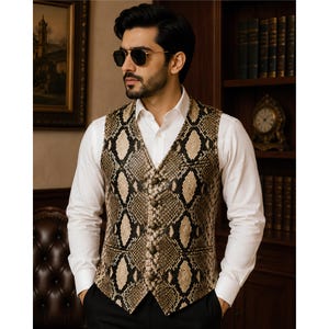 May include: A sleeveless vest featuring a tan and black snakeskin pattern, a V-neckline, and a front button closure. The garment is worn over a crisp white long-sleeved collared shirt, paired with dark trousers and dark-tinted sunglasses.