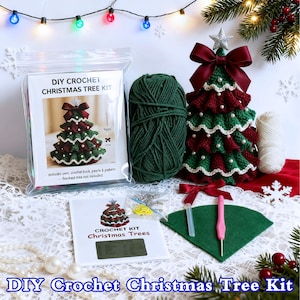 May include: A DIY crochet Christmas tree kit with a finished tree example. The kit includes yarn, crochet hook, pearls, and a pattern. The finished tree is red, green, and white, with a star on top. The kit is packaged with a green felt base and a pink crochet hook.