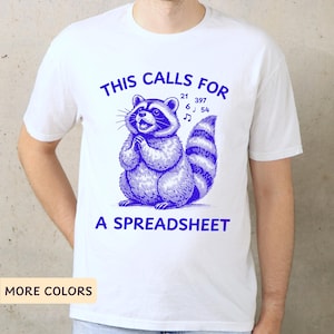 May include: White t-shirt with a blue illustration of a raccoon singing with musical notes and the text "This calls for a spreadsheet".