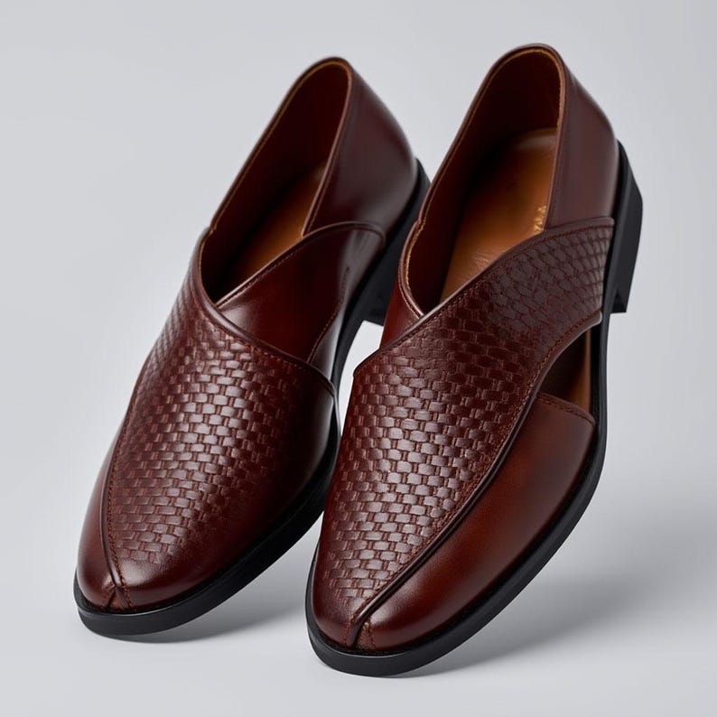 Pu&ograve; includere: Un paio di mocassini in pelle marrone scuro con una trama intrecciata sulla tomaia e una finitura liscia sui lati. Le scarpe presentano una punta affusolata, un dettaglio ritagliato sul lato e una suola nera. La fodera interna &egrave; marrone chiaro.