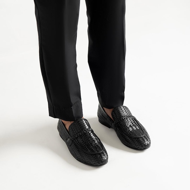 Premium black woven leather loafers for men worn with tailored trousers, showcasing luxury artisan craftsmanship, elegant braided penny loafer design, lightweight dress shoes, formal slip-on footwear, and timeless smart casual fashion styling.