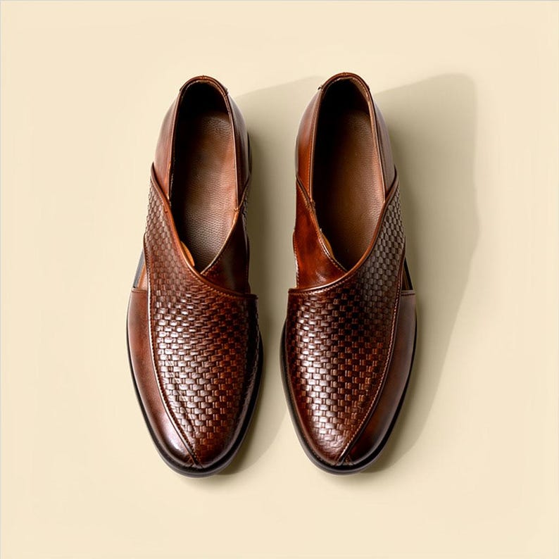 Pu&ograve; includere: Un paio di scarpe in pelle marrone con una trama intrecciata sulla tomaia e una finitura liscia sui lati. Le scarpe presentano una punta affusolata con una particolare costruzione a pannelli sovrapposti che crea una silhouette distintiva.