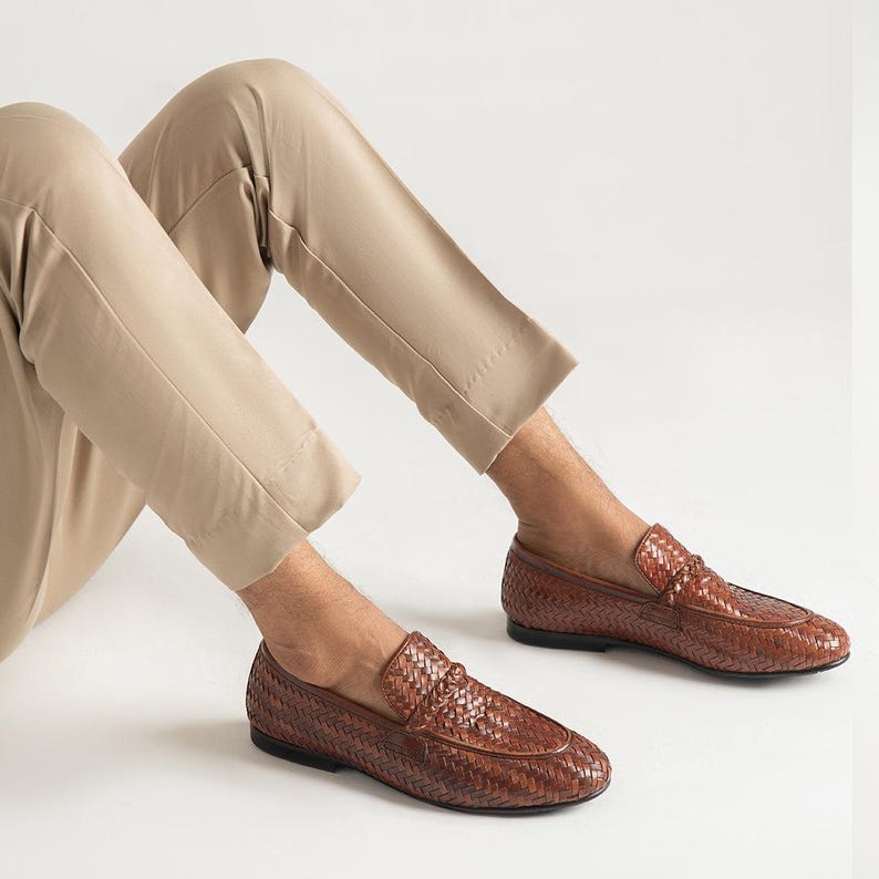 Men’s luxury woven leather loafers styled with beige trousers in modern smart casual outfit, featuring handcrafted braided leather design, elegant slip-on penny loafers, comfortable formal footwear, and sophisticated Italian-inspired men’s fashion shoes.
