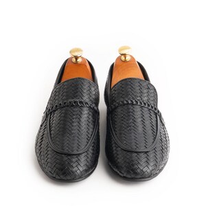 Front view of men’s woven leather loafers in rich black finish featuring braided penny strap detail, handcrafted formal slip-on shoes, luxury business casual footwear, elegant Italian-style moccasins, and premium artisan leather loafers.
