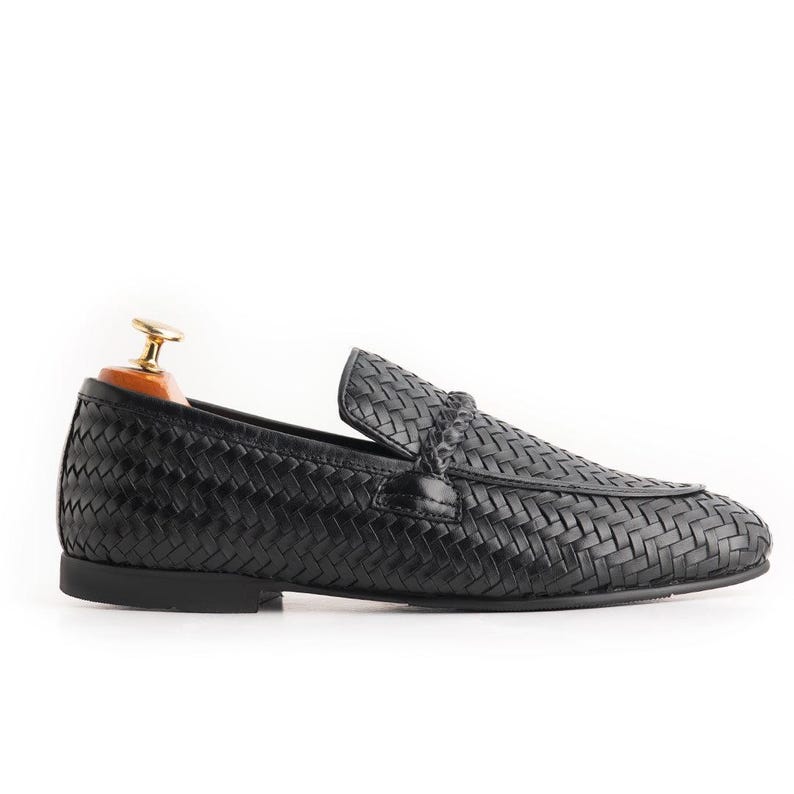 Side profile of handcrafted black woven leather loafers for men with sleek slip-on silhouette, soft leather lining, luxury braided texture, lightweight formal shoe design, Italian-inspired driving loafers, and timeless gentleman style footwear.