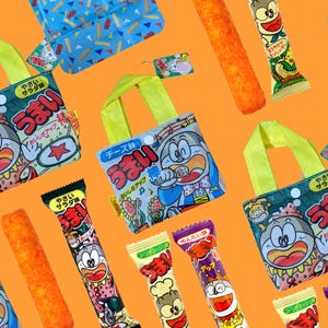 以下が含まれることがあります： オレンジ色の背景に、小さなトートバッグとスナックのパッケージがいくつかあります。トートバッグは黄色のハンドルと漫画のキャラクターが付いています。スナックのパッケージはカラフルで円筒形で、日本語のテキストと漫画のイラストが描かれています。