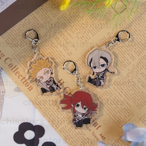以下が含まれることがあります： アニメスタイルのキャラクターデザインのアクリルキーホルダー。キーホルダーは、カラフルな髪と衣装のキャラクターが特徴です。それぞれにシルバーのキーリングが付いています。キャラクターには、扇子を持ったブロンド、灰色の髪のキャラクター、ハサミを持った赤毛のキャラクターが含まれます。