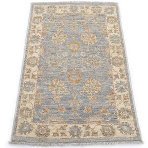 Könnte beinhalten: Ein rechteckiger, hellblauer Teppich mit einem komplizierten Blumenmuster in Beige und Orange. Der Teppich hat einen beigen Rand mit Fransen, geeignet für ein Wohn- oder Schlafzimmer. Der Teppich misst ca. 91 x 152 cm.