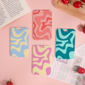May include: Four colorful luggage tags with wavy patterns. The tags feature designs in shades of blue, yellow, pink, and coral. Each tag has a rectangular shape with a small hole at the top for attachment.
