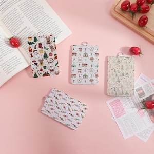 May include: Four rectangular keychains with festive patterns. One features snowmen, Christmas trees, and gifts. Another showcases a carnival scene with Ferris wheels. The third has a repeating leaf design, and the fourth has toy soldiers.