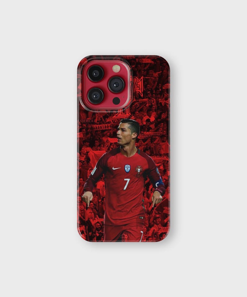 Puede incluir: Funda de tel&eacute;fono roja con la imagen de un futbolista con camiseta roja, n&uacute;mero 7. El fondo es un collage de im&aacute;genes rojas. La funda tiene un acabado brillante y un recorte para la c&aacute;mara.