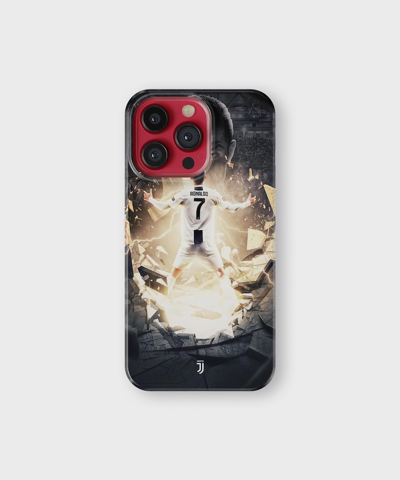 Puede incluir: Funda de tel&eacute;fono negra con un jugador de f&uacute;tbol con uniforme blanco y negro, n&uacute;mero 7 en la espalda. El dise&ntilde;o muestra al jugador rompiendo una pared con un efecto de luz brillante. La funda tiene un borde negro y un protector de lente rojo.
