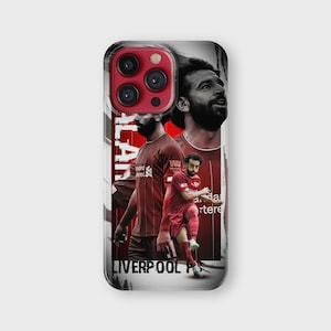 K&ouml;nnte beinhalten: Eine Handyh&uuml;lle mit einem Design, das einen Fu&szlig;ballspieler in einem roten Trikot zeigt. Auf der H&uuml;lle steht der Name "SALAH" vertikal auf der linken Seite und die Worte "LIVERPOOL FC" unten. Der Hintergrund ist eine Mischung aus Rot und Wei&szlig;.
