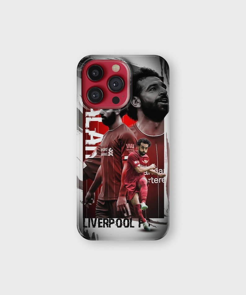 K&ouml;nnte beinhalten: Eine Handyh&uuml;lle mit einem Design, das einen Fu&szlig;ballspieler in einem roten Trikot zeigt. Auf der H&uuml;lle steht der Name "SALAH" vertikal auf der linken Seite und die Worte "LIVERPOOL FC" unten. Der Hintergrund ist eine Mischung aus Rot und Wei&szlig;.