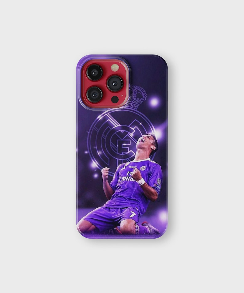 Puede incluir: Funda de tel&eacute;fono morada con un futbolista celebrando un gol. La funda tiene un fondo morado con el logo del Real Madrid y una corona. El jugador lleva una camiseta morada con el n&uacute;mero 7.