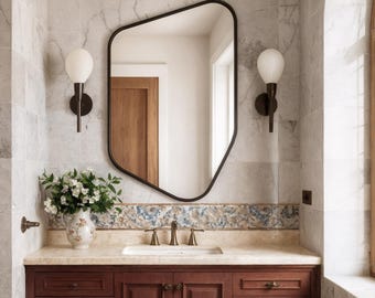 May include: A bathroom vanity with a dark wood cabinet, a marble countertop, and a white sink. A black-framed mirror hangs above the sink, and two sconces with globe lights flank the mirror. The walls are tiled with marble, and a window with a wooden frame is on the right.
