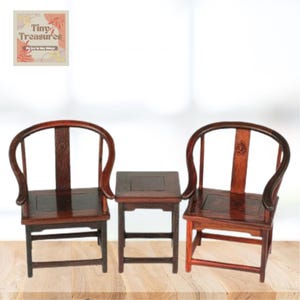 May include: A set of two dark wood chairs with curved backs and a matching square table. The chairs and table are made of dark wood with a smooth finish. The chairs have a simple design with a curved back and a square seat. The table has a square top and four legs.