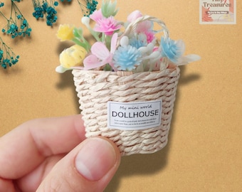 Könnte beinhalten: Ein Miniatur-Korb aus Weidengeflecht, gefüllt mit pastellfarbenen Blumen. Der Korb trägt ein Etikett mit der Aufschrift "My mini world DOLLHOUSE".
