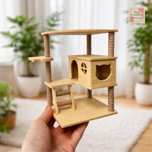 Könnte beinhalten: Ein Miniatur-Katzenbaum aus hellem Holz mit mehreren Ebenen, einem katzenförmigen Ausschnitt und einer kleinen Leiter. Die Struktur besteht aus hellem Holz mit seilumwickelten Pfosten. Der Baum hat eine kleine Plattform und eine obere Sitzfläche.