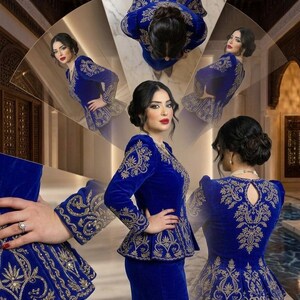 May include: A royal blue velvet ensemble featuring intricate gold embroidery. The outfit includes a fitted jacket with a peplum and a matching skirt. The sleeves and jacket are adorned with detailed floral patterns. The overall design is elegant and formal.