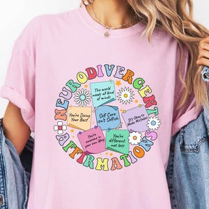 a woman wearing a pink t - shirt with the words love is all around her