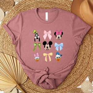 a pink tshirt with mickey mouse and other disney characters on it