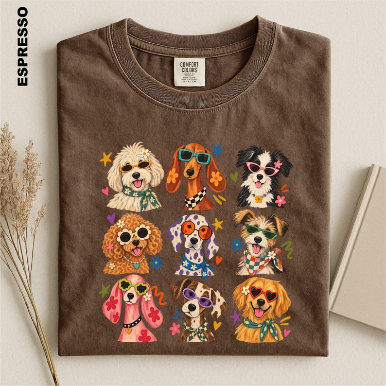 Puede incluir: Una camiseta de cuello redondo color marr&oacute;n oscuro con un estampado gr&aacute;fico de nueve razas de perros diferentes que llevan gafas de sol coloridas y accesorios florales. La camiseta tiene una etiqueta Comfort Colors y la palabra ESPRESSO a la izquierda.