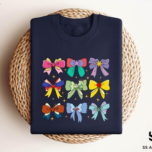 a navy blue t - shirt with colorful bows on it