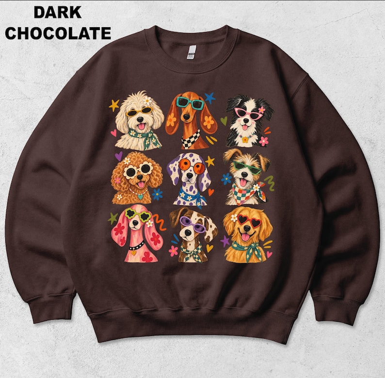 Puede incluir: Una sudadera de cuello redondo color marr&oacute;n chocolate oscuro con un estampado gr&aacute;fico de nueve perros con gafas de sol coloridas y pa&ntilde;uelos o collares estampados, rodeados de iconos de estrellas, corazones y flores. El texto DARK CHOCOLATE es visible.