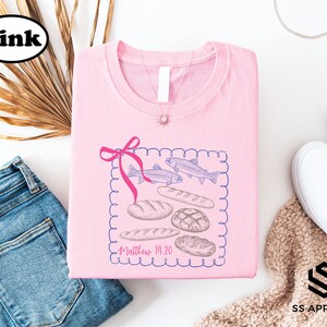 a pink t-shirt with a graphic design, a pair of blue jeans, a pair of white sneakers, and some decorative elements such as a plant and a ribbon.