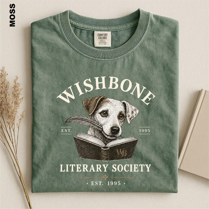 A green t-shirt with a graphic design featuring a dog holding a book, along with text that reads "Wishbone Literary Society" and "Est. 1995".
