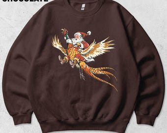 Op de afbeelding: Een donkerchocoladebruine sweater met ronde hals en een grafische print van de Kerstman die op een vliegende fazant rijdt. De tekst "DARK CHOCOLATE" staat in de linkerbovenhoek. De sweater heeft lange mouwen.
