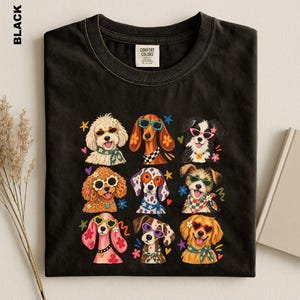 Puede incluir: Una camiseta negra con un estampado gr&aacute;fico de nueve razas de perros diferentes, cada una con gafas de sol coloridas y pa&ntilde;uelos o collares estampados. El dise&ntilde;o incluye peque&ntilde;os detalles de estrellas y flores. La camiseta tiene una etiqueta Comfort Colors.